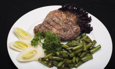 Bir parça biftek ve yeşil salata.