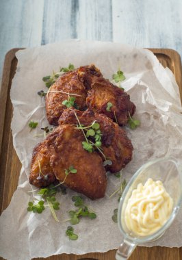 Tahta arka planda beyaz bir tabakta kızarmış tavuk bacağı.