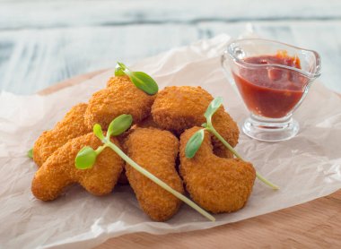 Tavuk külçeleri beyaz tabakta, ahşap arka planda sos var..