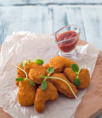 Ahşap arka planda ketçaplı tavuk külçeleri.