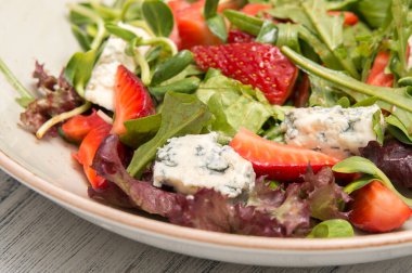 Arugula ve ahşap arka planda çilekli taze salata.
