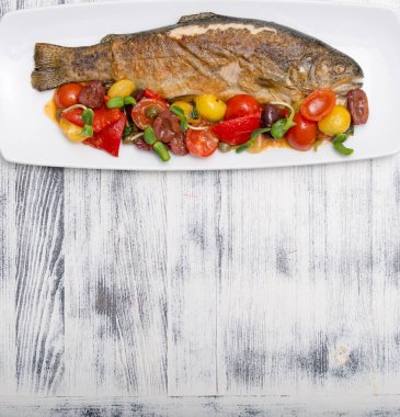 Tabağında sebze olan ızgara alabalık.