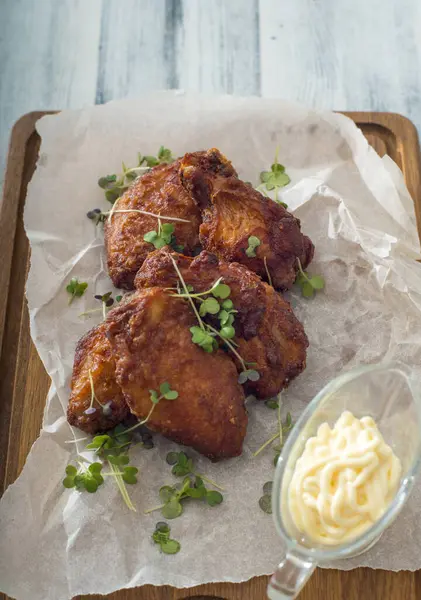 Tahta arka planda beyaz bir tabakta kızarmış tavuk bacağı.