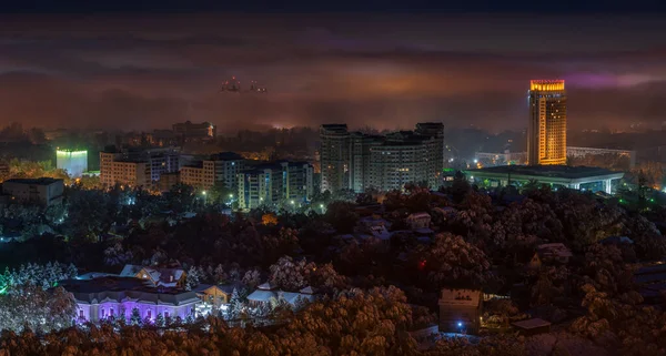 stock image The central part of the city of Almaty (Kazakhstan) after the fallen snow and fog in the background late at night