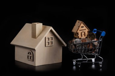 Tahta sembolik evler ve siyah arka planda Amerikan sikkeleri olan minyatür bir araba.