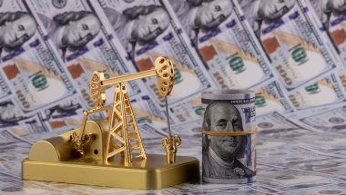 Golden oil pump on the background of 100 American dollars bills