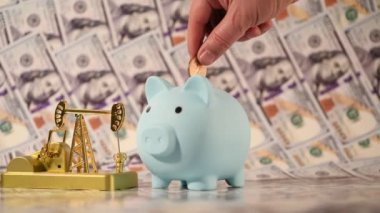 A miniature gold oil pump against the background of 100 US dollar bills