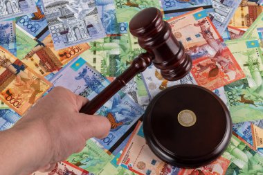Judge's gavel and Kazakhstani coin in denominations of 100 tenge against the background of Kazakhstani tenge