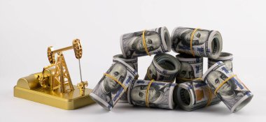 Gold oil pump model and rolled up 100 american dollar bills