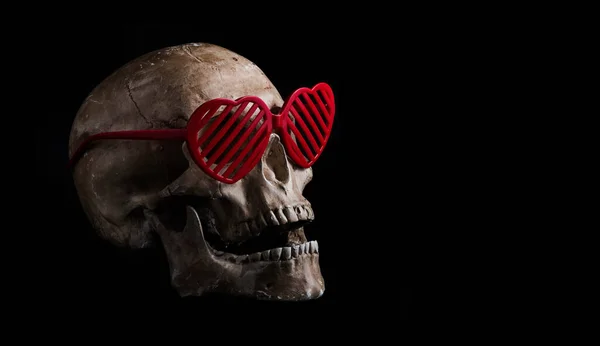 Model of a human skull with glasses with symbolic human hearts on a black background