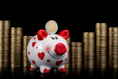 A funny piggy bank and a coin of 200 Kazakhstani tenge against the background of stacked coins
