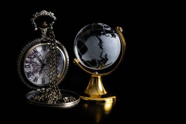 Crystal globe and vintage antique pocket watch on black background