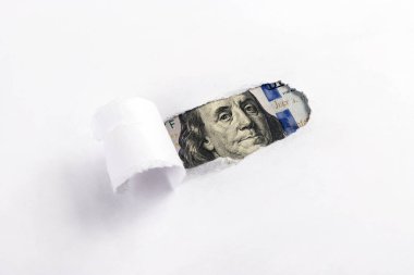 A fragment of a banknote in denominations of 100 American dollars in a hole on a sheet of paper