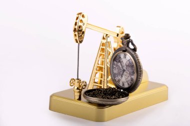 Golden oil pump and vintage pocket watch isolated on white background