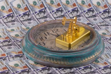 Altın yağ pompası ve antika duvar saati Amerikan dolarlarının arka planında.