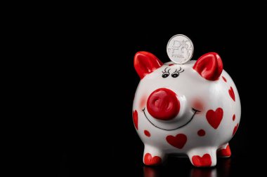 Rus rublesinin sembolü olan 1 rublelik sikke ve siyah arka planda komik bir kumbara.