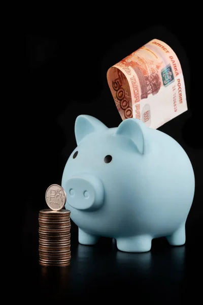 Stock image Piggy bank and coin with Russian ruble symbol on black background