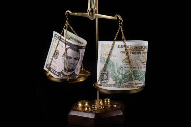 Banknotlar beş Amerikan doları, beş Kolombiya pezosu ve terazisi.
