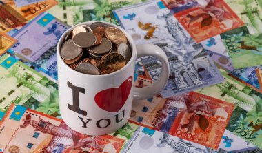 Çay fincanındaki Amerikan sikkeleri Kazak banknotlarının arka planına karşı - tenge