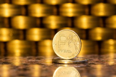 Birikmiş altın paraların arka planında Rus para biriminin sembolü olan 1 Rus rublesi.