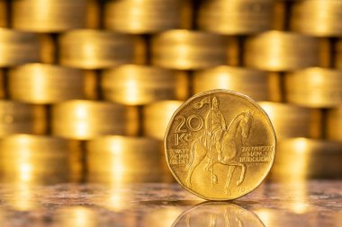 Coin in denomination of 20 Czech crowns against the background of a wall of gold coins