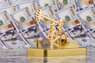 Suudi Arabistan Krallığı 'ndan 1 riyal ve 100 Amerikan doları değerinde banknotların arka planına karşı altın bir petrol pompası.