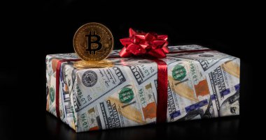 Şifreli para birimi Bitcoin 'in sembolü ve 100 Amerikan doları değerinde banknotların görüntüsü olan bir hediye kutusu.