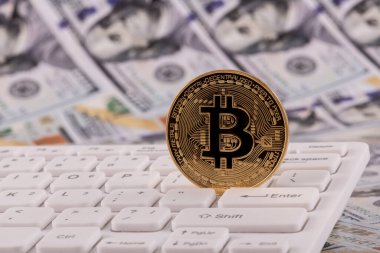 Bitcoin kripto para sembolü, bilgisayar klavyesi ve 100 Amerikan doları banknotlu altın sikke