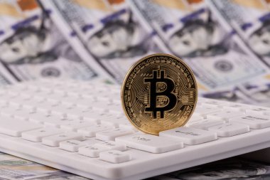 Bitcoin kripto para sembolü, bilgisayar klavyesi ve 100 Amerikan doları banknotlu altın sikke
