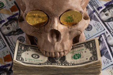 Bir insan kafatasının göz çukurunda Bitcoin kripto para sembolü olan bir altın sikke 100 Amerikan dolarının arka planına karşı.