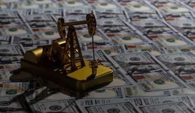 Golden oil pump on the background of 100 American dollars bills