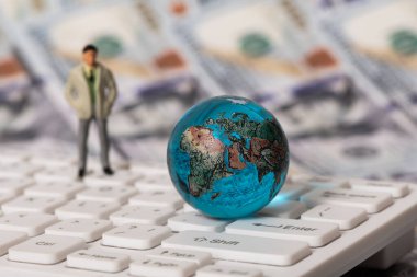 100 dolarlık banknotların arka planına karşılık bilgisayar klavyesindeki cam küre.
