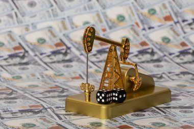 Altın petrol pompası ve zarlar 100 Amerikan dolarının arka planına karşı.