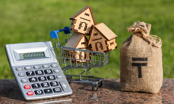 stock image Money bag with Kazakh currency symbol - tenge, miniature wooden houses and calculator