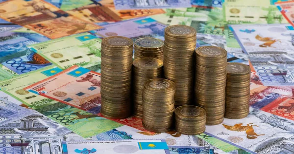 Kazakistan banknotlarının arka planına karşılık 100 Kazakistan madeni para sütunları.