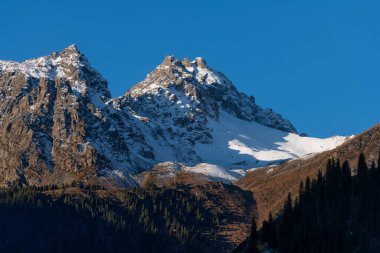 Bir sonbahar sabahı Almaty civarındaki Trans-Ili Almaty dağlarında karla kaplı çift başlı zirve.