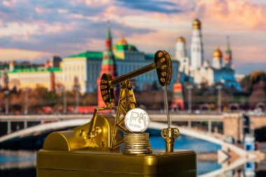 Moskovalı Kremlin 'in arka planında Rus rublesinin sembolü olan minyatür altın petrol pompası ve sikke.