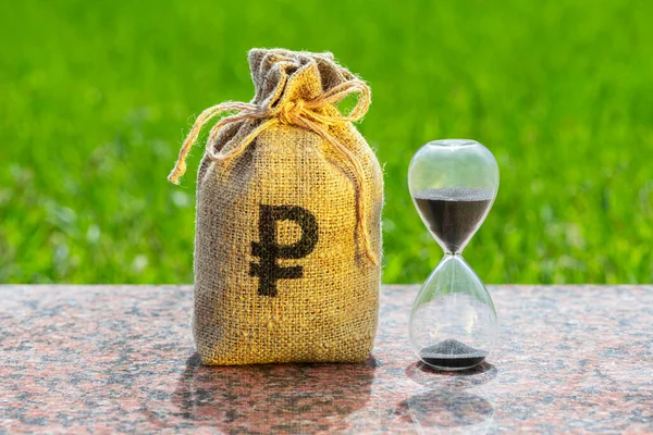 Hourglass and money bag with Russian ruble symbol