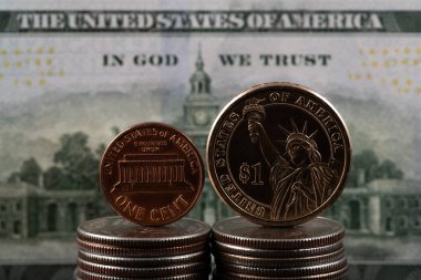 100 dolarlık banknotun arka planına karşılık 1 sent ve 1 Amerikan doları değerindeki paralar.