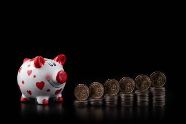 Üzerinde Özgürlük Anıtı resmi olan 1 Amerikan doları sikkeleri ve siyah arka planda insan kalbi sembolü olan komik bir domuz kumbarası.