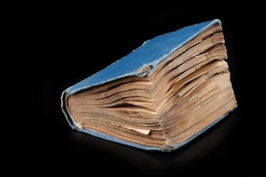 Siyah arka planda sarı sayfaları olan eski püskü bir kitap.