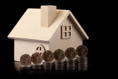 1 Amerikan doları sikkeleri ve siyah arka planda sembolik ahşap bir ev.