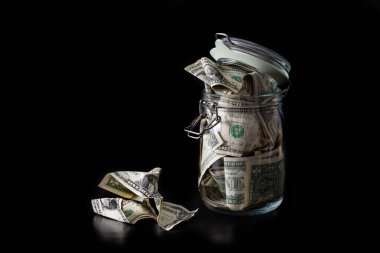 Siyah arka planda 1 Amerikan doları olan cam kavanozu temizleyin.