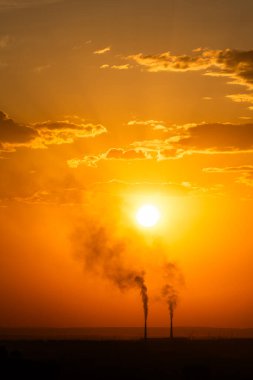 Gün batımında kömürle çalışan bir santralin bacalarını yakmak.