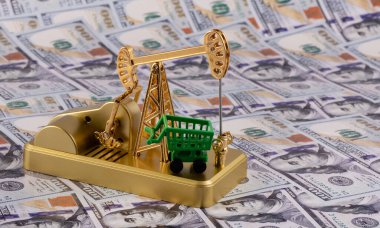 Altın minyatür yağ pompası ve 100 dolarlık banknotlarla dolu alışveriş arabası.