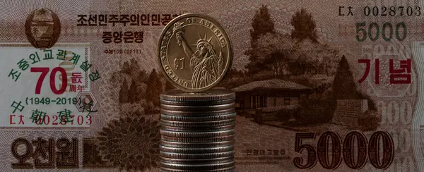 A bill of 5000 North Korean won and 1 US dollar coin