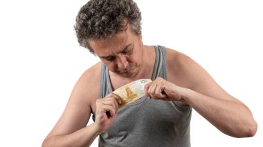 A gray-haired, shaggy, unshaven middle-aged man in a sleeveless T-shirt holds a 100 Russian ruble bill clipart