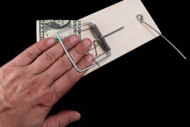 Adamın parmakları fare kapanına yakalanmış ve siyah arka planda 1 Amerikan doları var.