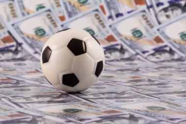 Arkasında 100 dolarlık banknotlar olan minyatür futbol topu.