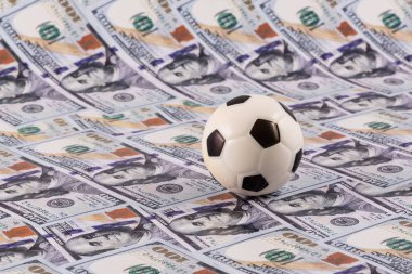 Arkasında 100 dolarlık banknotlar olan minyatür futbol topu.